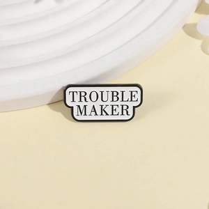 Détail d'un badge en émail avec texte Trouble Maker sur une assiette décorative