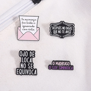 Détail de quatre épinglettes en émail coloré avec citations sur sac en toile blanche