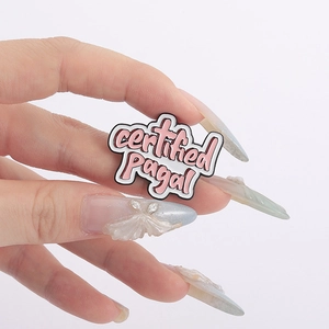 Macro shot of an enamel cloud brooch featuring the text certified Pagal in pink and white