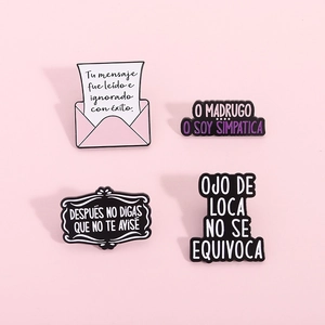 Détails de quatre broches en émail avec des citations espagnoles sur fond rose