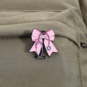 Macro detail of a pink butterfly stethoscope enamel pin on olive canvas fabric background