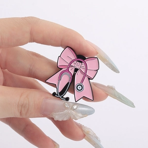 Detailed view of a pink bow enamel brooch with stethoscope pattern held in hand