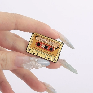 Detail shot of a retro yellow enamel cassette tape pin with Chill Out text engraving
