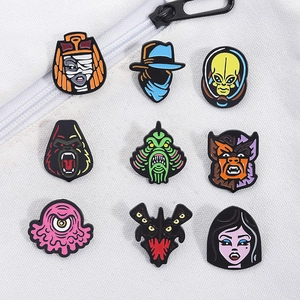 Detailed set of nine cartoon monster enamel pins displayed on white canvas fabric background