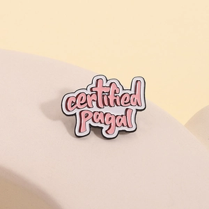 Macro di una spilla in smalto 'certified pagal' con scritta rosa su base bianca
