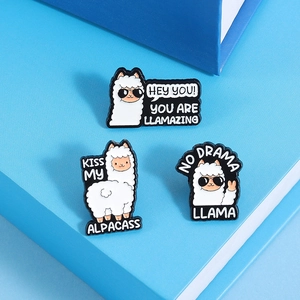 Detailed view of three alpaca enamel pins featuring sunglasses and fun text on blue background