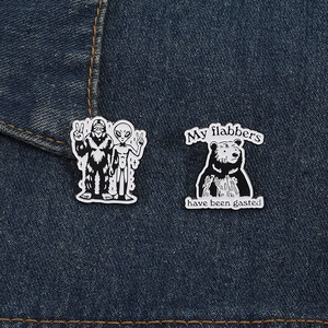 Close-up of funny alien and bear enamel pins pinned on a blue denim jacket texture