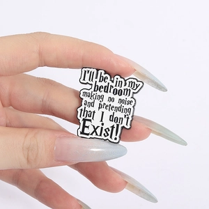 Macro shot of black enamel pin with movie quote text held by hand on white background