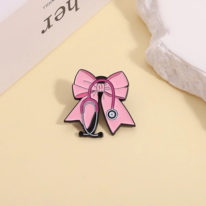 Macro detail of a pink bow and stethoscope enamel brooch pin on a white textured stone