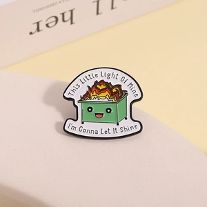 Macro detail of enamel dumpster fire pin with humor quote on a warm background