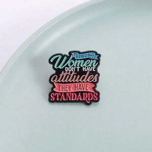 Makroaufnahme der Emaille-Anstecknadel mit dem Text Strong Women Don't Have Attitudes