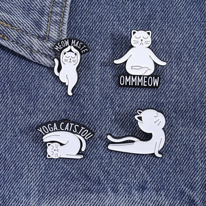 Détail de quatre pins en émail de chats blancs faisant du yoga sur tissu denim bleu