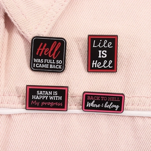 Detail of four black enamel humor pins with witty text on light pink denim fabric