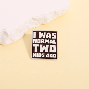 Square enamel pin with 'I WAS NORMAL TWO KIDS AGO' humor quote in black and white