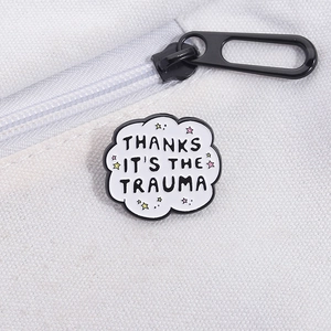 Close-up of enamel cloud pin with trauma quote on white canvas bag texture