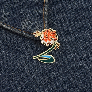 Detailaufnahme einer bunten Emaille-Brosche in Blumenform an einer blauen Jeansjacke