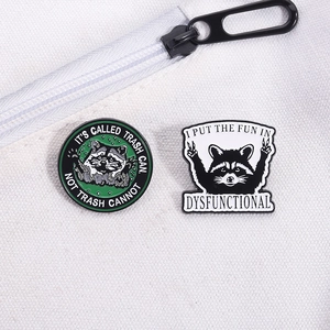 Detail of funny raccoon enamel pins with motivational quotes pinned to a canvas bag