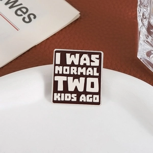 Square enamel pin with I Was Normal Two Kids Ago text on leather background