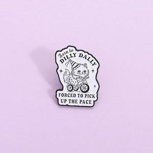 Cartoon cat on tricycle enamel pin with Born to Dilly Dally slogan on purple background