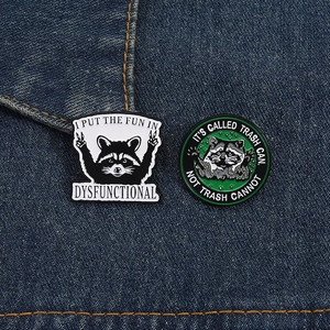 Detailed close-up of raccoon skeleton enamel pins on blue denim fabric with witty puns
