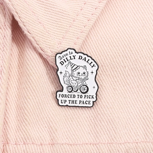 Macro shot of a cartoon cat enamel pin with English quotes on pink denim fabric