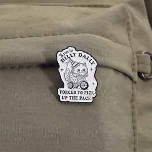 Cartoon black cat on tricycle enamel pin with Born to Dilly Dally quote on backpack