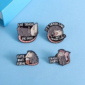 Vier Opossum-Emaille-Pins mit humorvollen Slogans auf hellblauem Hintergrund