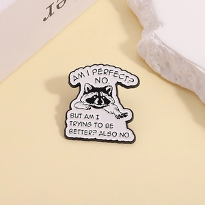 Detail shot of a black and white enamel raccoon pin with witty quote on a cream background