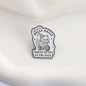 Detail of enamel cat brooch with Born to Dilly Dally text on white decorative tray