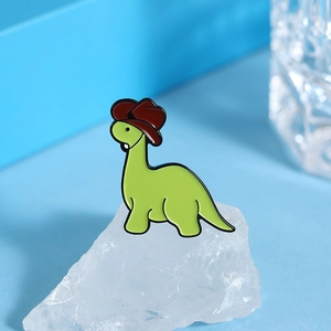 Macro shot of green dinosaur enamel pin with cowboy hat on a blue crystal background