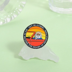Detail of Karl Marx enamel pin with 'Get In Loser' text on a light green background