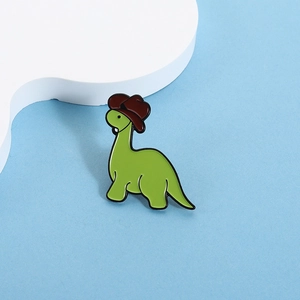 Cute green cartoon dinosaur enamel pin wearing a brown cowboy hat on blue background