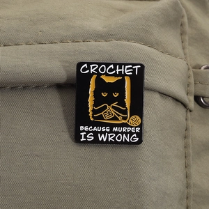 Détail d'un pin's chat en émail noir sur sac en toile avec citation humour crochet