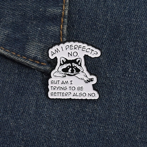 Detail of creative raccoon enamel pin with humorous quote on dark blue denim fabric