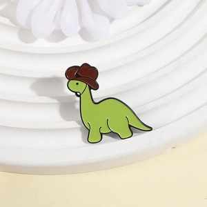 Cute green cartoon dinosaur enamel pin wearing a brown cowboy hat on white display