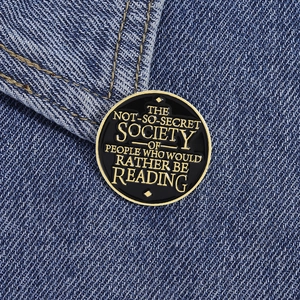 Détail du pin's émaillé avec slogan de lecture épinglé sur un tissu en jean bleu