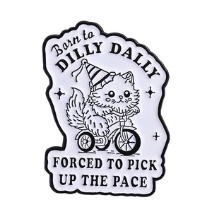 Cartoon kitten riding tricycle enamel pin with Born to Dilly Dally slogan on white backdrop