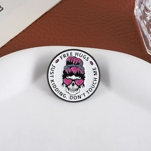Punk style round skull metal brooch with FREE HUGS text on a white porcelain plate