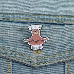Yoga sloth enamel pin with Let That Shit Go text on denim jacket pocket