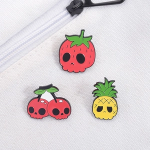 Detailed view of skull-faced strawberry, cherry, and pineapple enamel pins on canvas