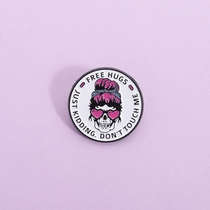 Pink skull enamel pin with Free Hugs text on a lavender background for jackets