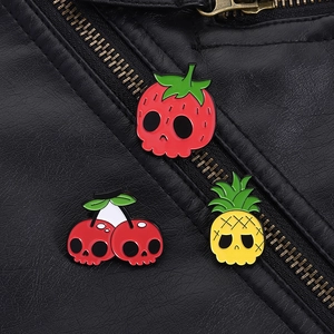 Detail of strawberry and pineapple skull enamel pins on a black leather jacket