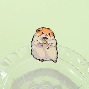 Detailed close-up of a cartoon hamster enamel pin holding a golden cross on a green base