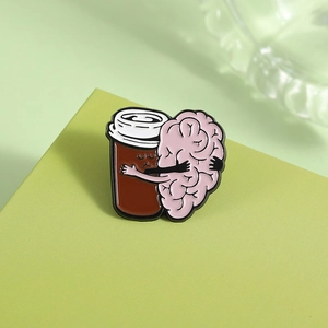 Détail d'une broche en émail tasse de café avec un cerveau sur un socle vert