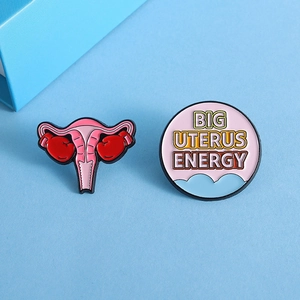 Uterus enamel pin set with boxing gloves and Big Uterus Energy slogan on blue background