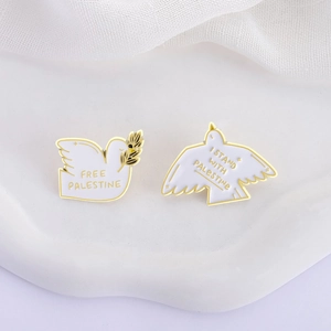 Close-up of white enamel pigeon badges with Free Palestine text and golden olive branch