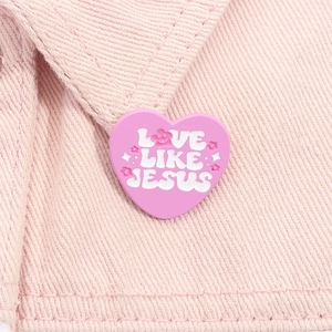 Macro de broche cœur rose avec texte Love Like Jesus sur tissu en denim rose