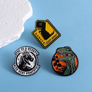 Three creative cartoon dinosaur enamel pins with danger sign and crown dinosaur designs