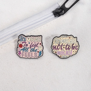 Close-up of motivational enamel pins with quotes pinned on a white canvas bag