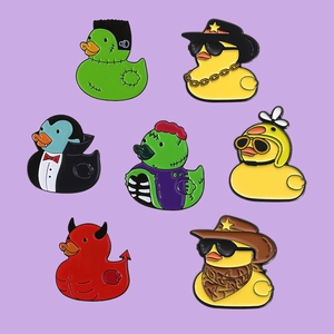 Set of enamel pins featuring cute rubber ducks in science, vampire and cowboy costumes